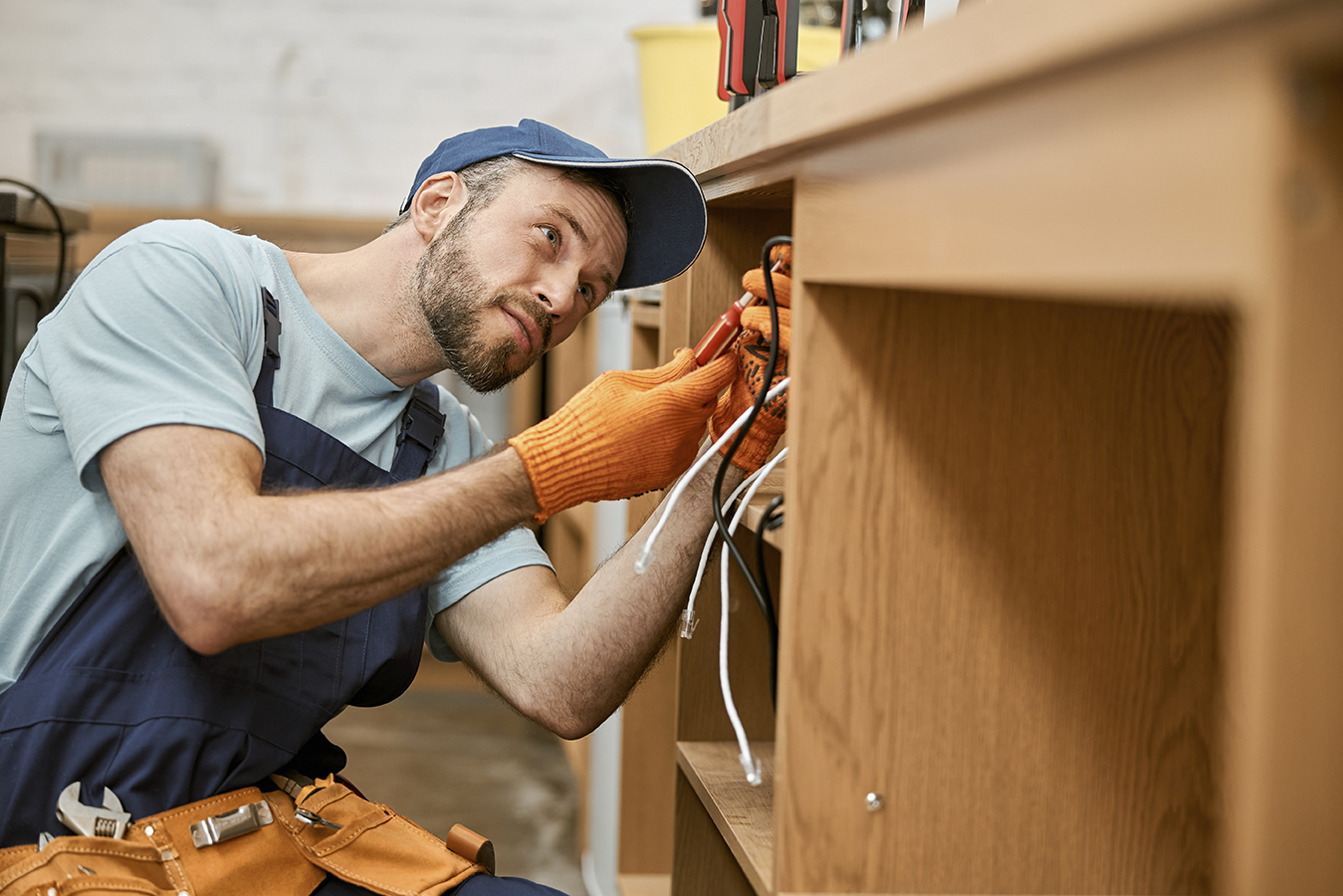 Bearded male electrician repairing desk electrical cable
